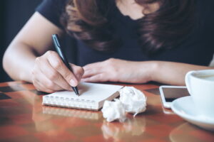 Lady writing notes onto notepad with scrunch paper around