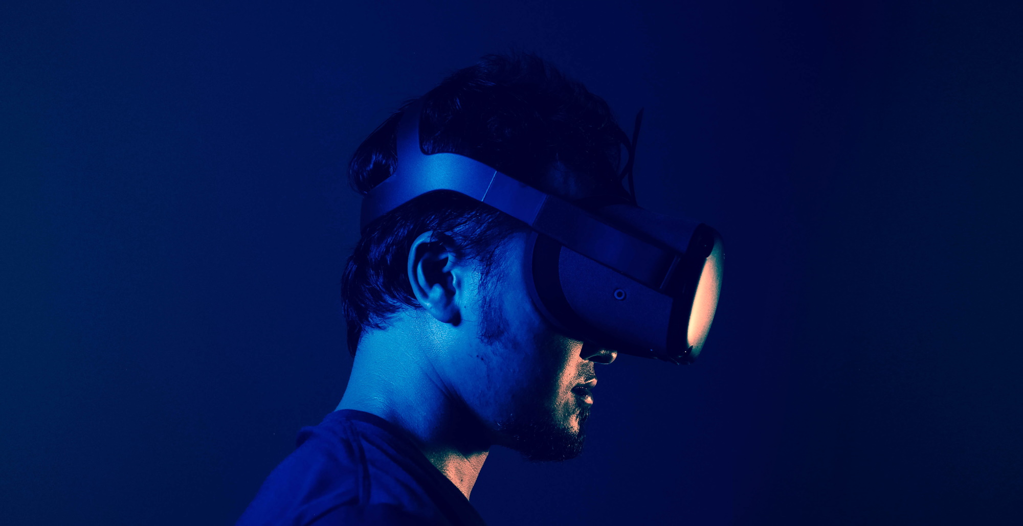 male wearing a VR headset in a blue room with blue lighting