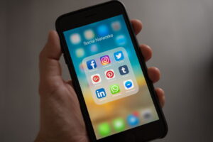 hand holding phone displaying social media apps - Social Media Marketing 