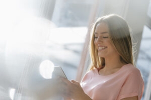 Portrait of laughing young woman looking at cell phone